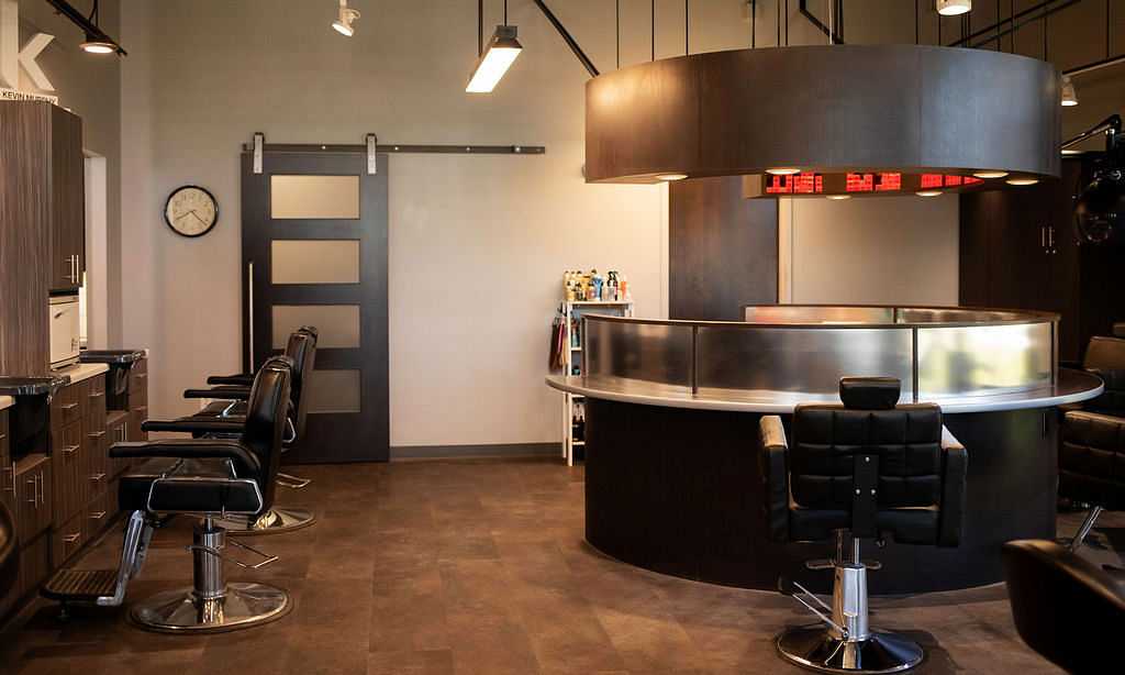Barbershop interior with modern decor, leather chairs, and a sleek reception desk.